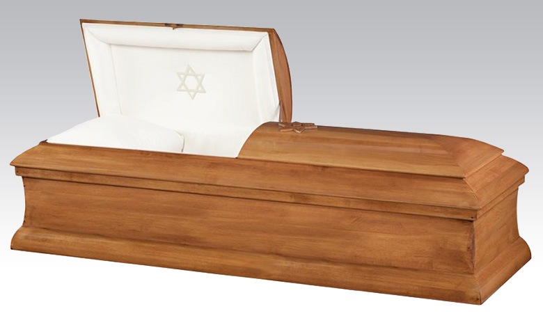 A wooden casket, part of the burial merchandise, with a partially open lid reveals a white interior and pillow. A Star of David is embroidered on the inside of the lid.
