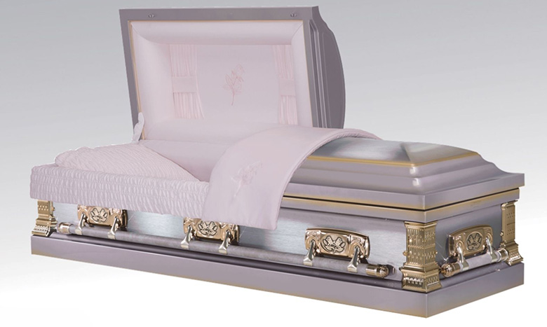 A silver and gold casket with intricate handles and detailing is shown partially open, revealing a padded white interior with a pillow and blanket—an elegant example of premium burial merchandise.