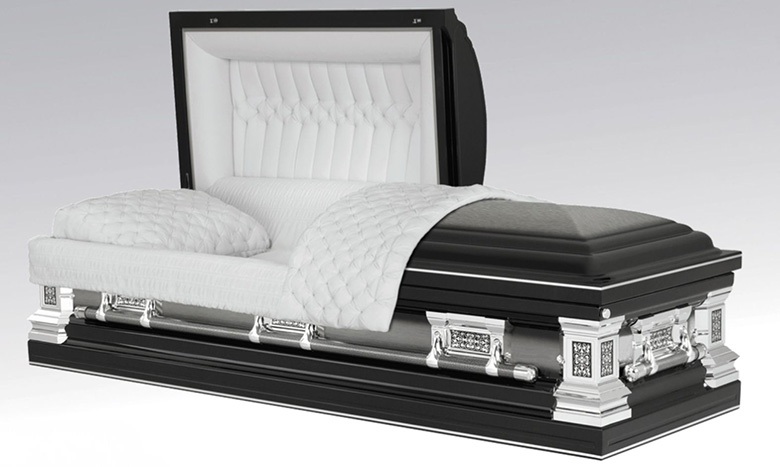 A luxurious black and silver casket, part of premium burial merchandise, is open to reveal a plush white interior with quilted lining and a folded blanket with pillow, resembling an elegant bed.