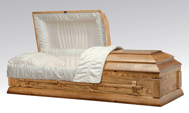 A wooden casket, a classic piece of burial merchandise, with a partially open lid is lined with white fabric and padding, displayed on a plain light background.