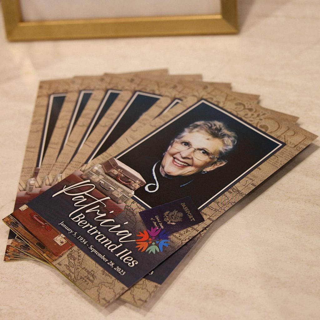 A stack of memorial service programs on a table honors Patricia Bernard Niles (January 7, 1934 – September 23, 2023), featuring her smiling portrait—a touching tribute to her life celebrations.